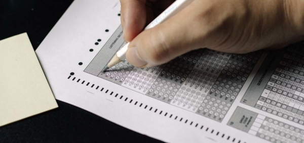 Close-up of a student's hand filling in a bubble on a PSAT scantron.